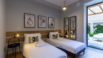A hotel room with two beds, a wooden headboard, a desk with a chair, and framed artwork on the wall.