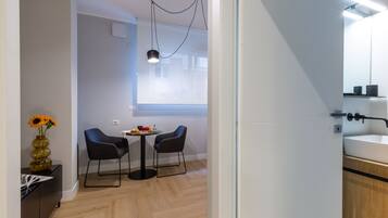A modern room with a dining area, a small table with two chairs, a vase with flowers, and a window with a view.