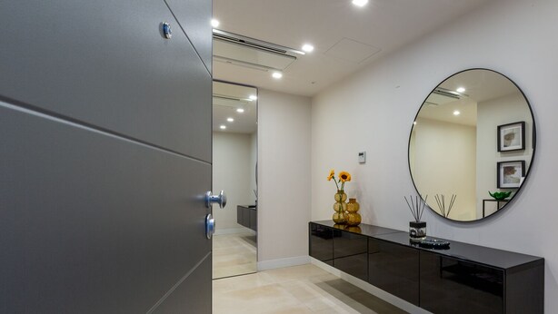 A modern hallway with a mirrored wall, a black console table, and a grey wardrobe. - Casa Lounge 43 (Cagliari)