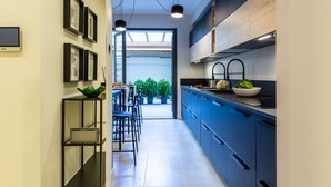 A modern kitchen with blue cabinets, a black countertop, and a skylight above the dining area. - Casa Lounge 43 (Cagliari)