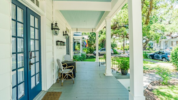 A porch with a blue door, wicker chairs, and a potted plant. - Spacious Midtown Home, Walk to Mardi Gras, Pets Ok
 (Mobile)