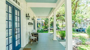 A porch with a blue door, wicker chairs, and a potted plant.
