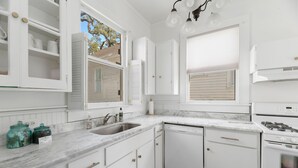 A kitchen with white cabinets, a marble countertop, a gas stove, and a sink. - Spacious Midtown Home, Walk to Mardi Gras, Pets Ok
 (Mobile)