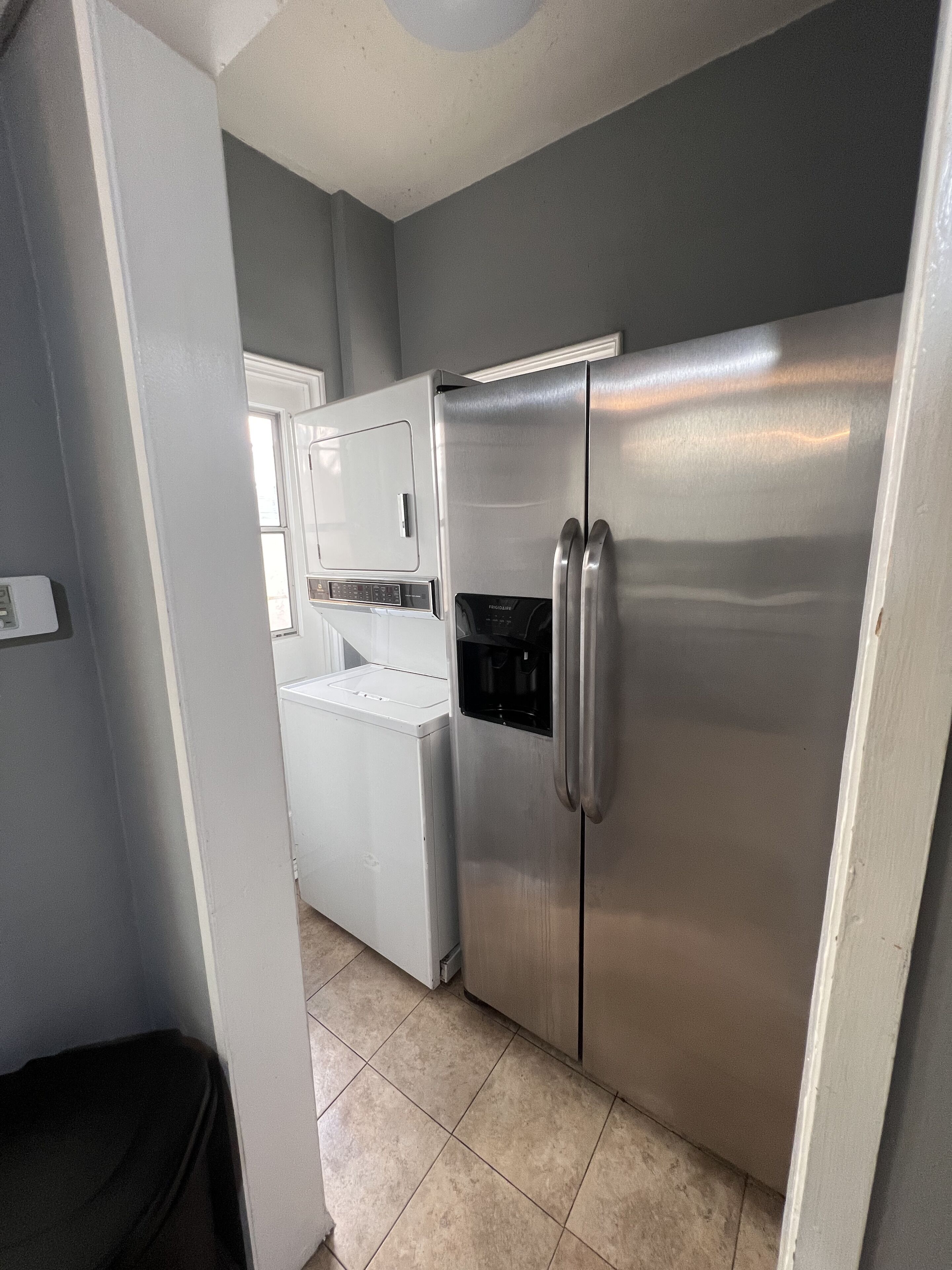 A compact kitchen with a stainless steel refrigerator, a built-in oven, and a washing machine.