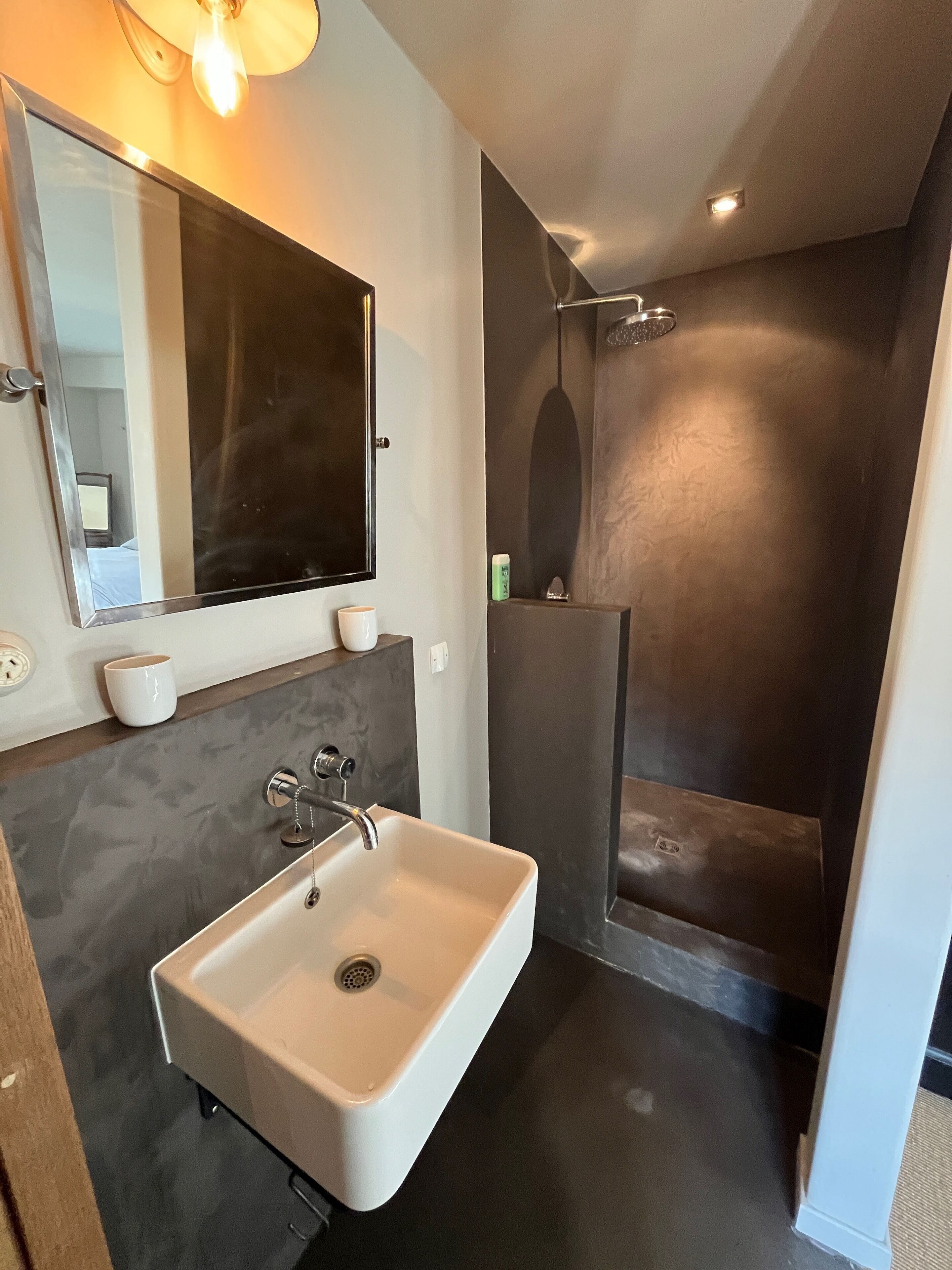 Een moderne badkamer met een ruime wastafel, een spiegel en een douchehoek.