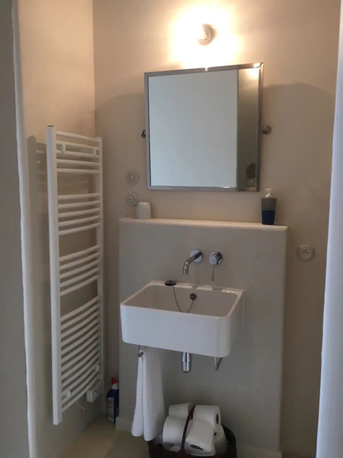 Een badkamer met een wit wastafelmeubel, een spiegel erboven en een handdoekhouder aan de linkerkant.