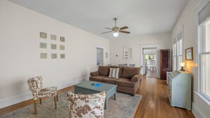 Ein Wohnzimmer mit einer Couch, zwei Sesseln, einem Couchtisch und einem Deckenventilator.