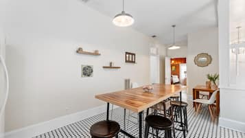 A dining area with a wooden table, black and white patterned floor, and pendant lighting.