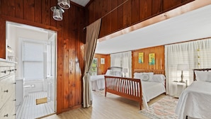 A wooden-paneled bedroom with two beds, a dresser, and a walk-in closet.