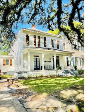 A two-story house with a front porch, a chimney, and a well-maintained lawn.
