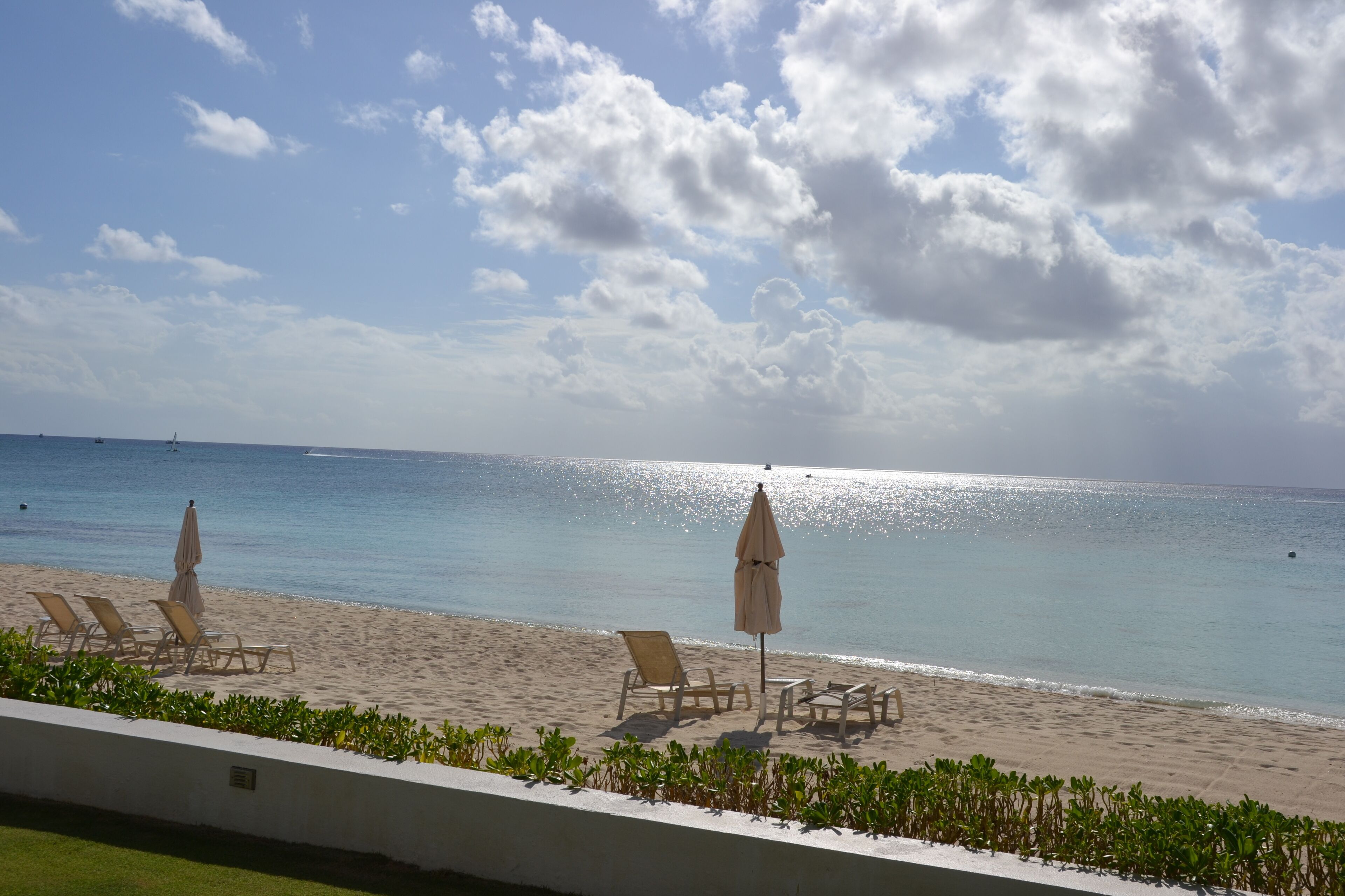 A beach with lounge chairs and umbrellas, a clear sky, and the ocean.