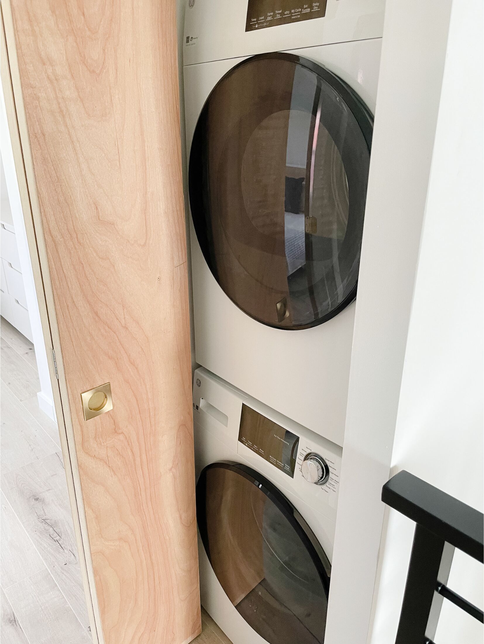 Un lavadero moderno con dos lavadoras de carga frontal y una puerta de madera.