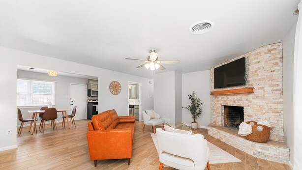 Una sala moderna con chimenea, un comedor y una cocina al fondo.