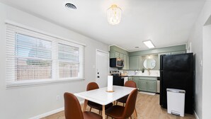 Una cocina moderna con una mesa de comedor, sillas y un refrigerador negro.