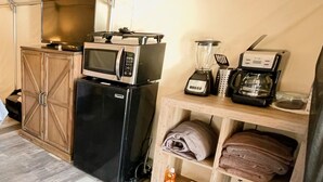 Una cucina compatta con microonde, frigorifero, frullatore e macchina da caffè.