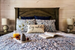 Relax in this inviting bedroom with a patterned duvet, wooden headboard, and bedside lamps.
