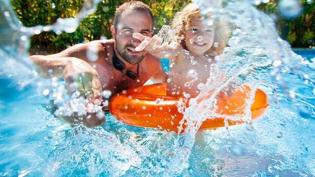 A swimming pool with clear water and visible bubbles, surrounded by greenery. - Villas at Seven Dwarfs (Kissimmee)