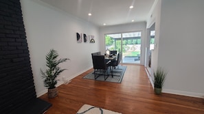 A modern interior with a dining area, wooden flooring, and a black brick accent wall.