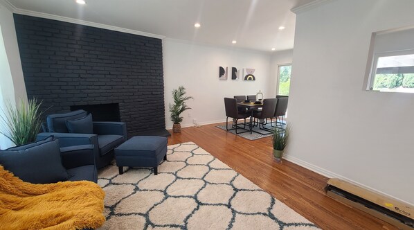 A modern living room with a black brick fireplace, a sofa, and a dining area with a table and chairs.