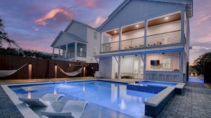A two-story house with a swimming pool, outdoor seating, and a covered patio area.