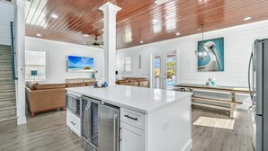A modern kitchen with a central island, stainless steel appliances, and a wooden ceiling.