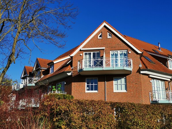 A two-story brick house with a balcony, a chimney, and a clear blue sky.