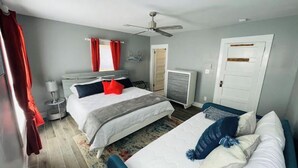 Une chambre d’hôtel avec deux lits, un ventilateur de plafond, une télévision et une porte.