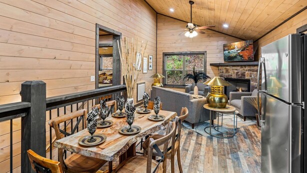 A cozy cabin interior with a dining area, a fireplace, and a kitchen. - Great Location, 3 min To Parkway! Private Hot Tub,Arcade, Fireplace,shuffleboard (Pigeon Forge)