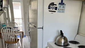 Eine Küche mit weißem Kühlschrank, Herd und einem Essbereich mit Holzstuhl und Tisch.