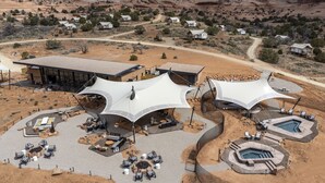 A desert resort with multiple tents, a pool, and a building with a large glass facade. - ULUM Moab (La Sal)
