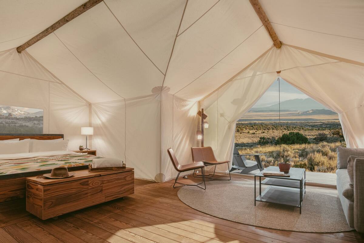Una habitación con tienda de campaña, una cama, una silla, una mesa y vistas al paisaje.