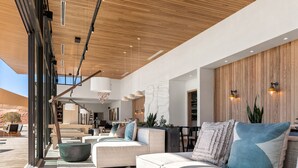 A modern living area with a wooden ceiling, large windows, and a sofa with cushions. - ULUM Moab (La Sal)
