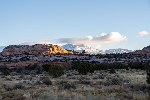 Un paysage montagneux avec une formation rocheuse imposante au premier plan et des sommets enneigés en arrière-plan.