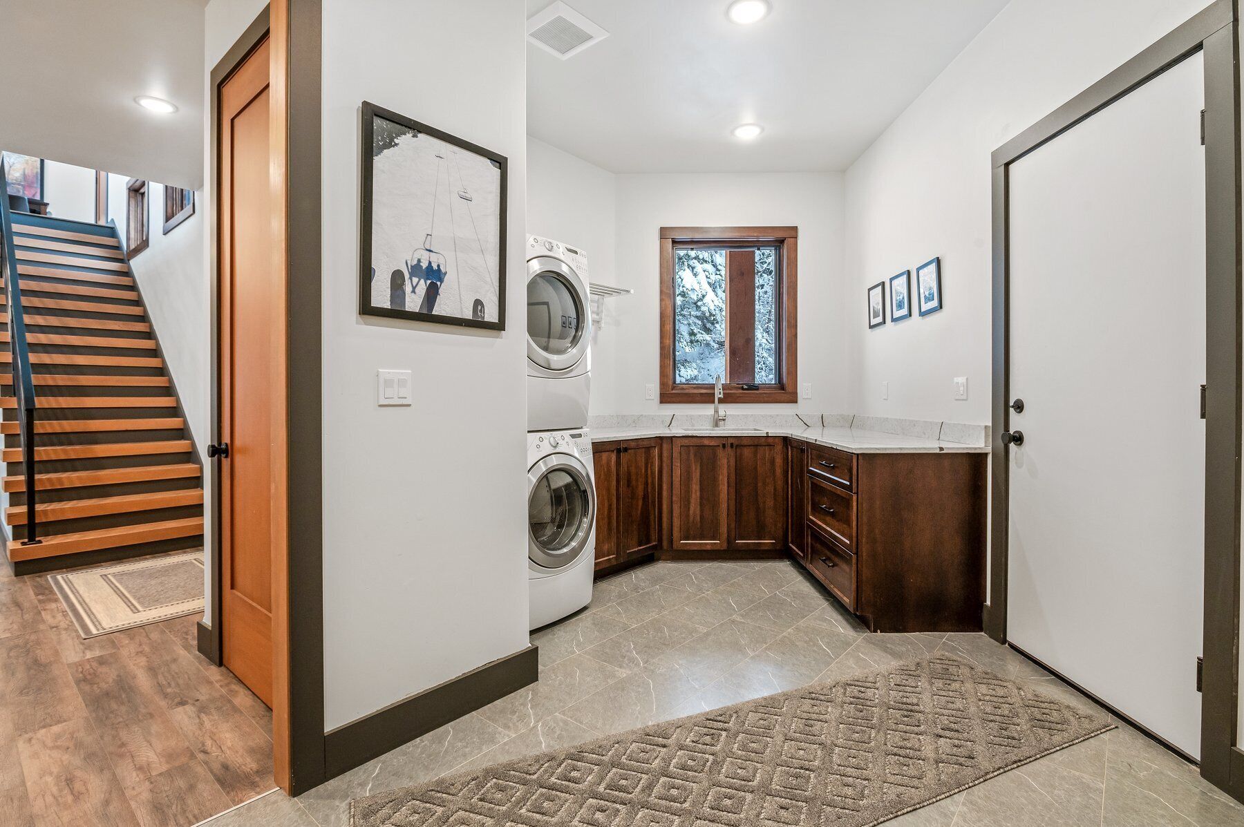 A laundry room with a washing machine, dryer, and a window with a view of trees.