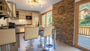 A modern kitchen with bar stools, a large window, and a rustic brick wall. - Chalet Gaïla spacious chalet in Les Allues next to the gondola (Meribel Les Allues)