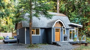 A small cabin with a sloped roof, a front porch, and a garage.
