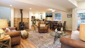 A cozy living room with a fireplace, a dining area, and a kitchen.