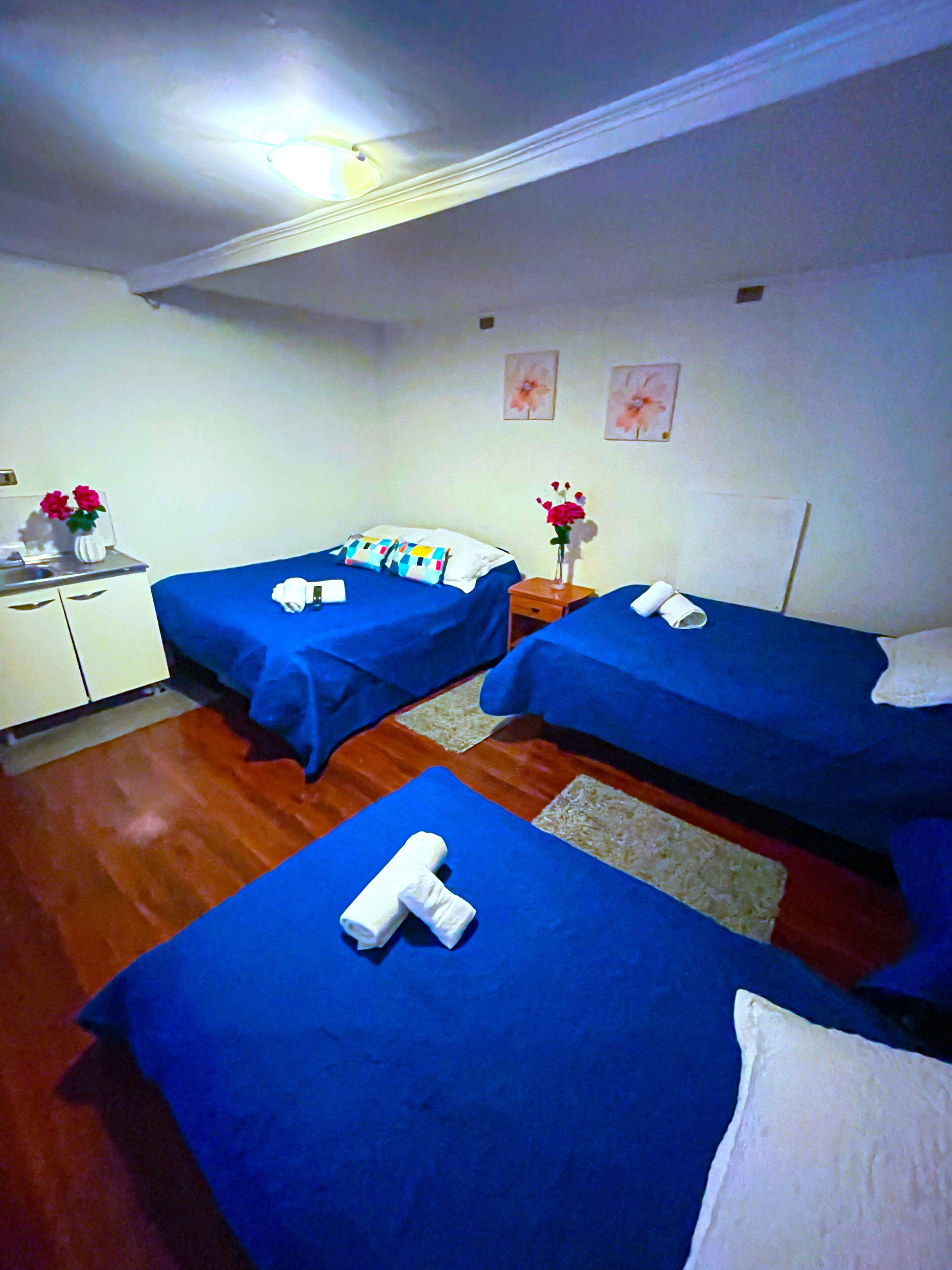 A hotel room with two single beds, a small desk, and a nightstand with a vase of flowers.