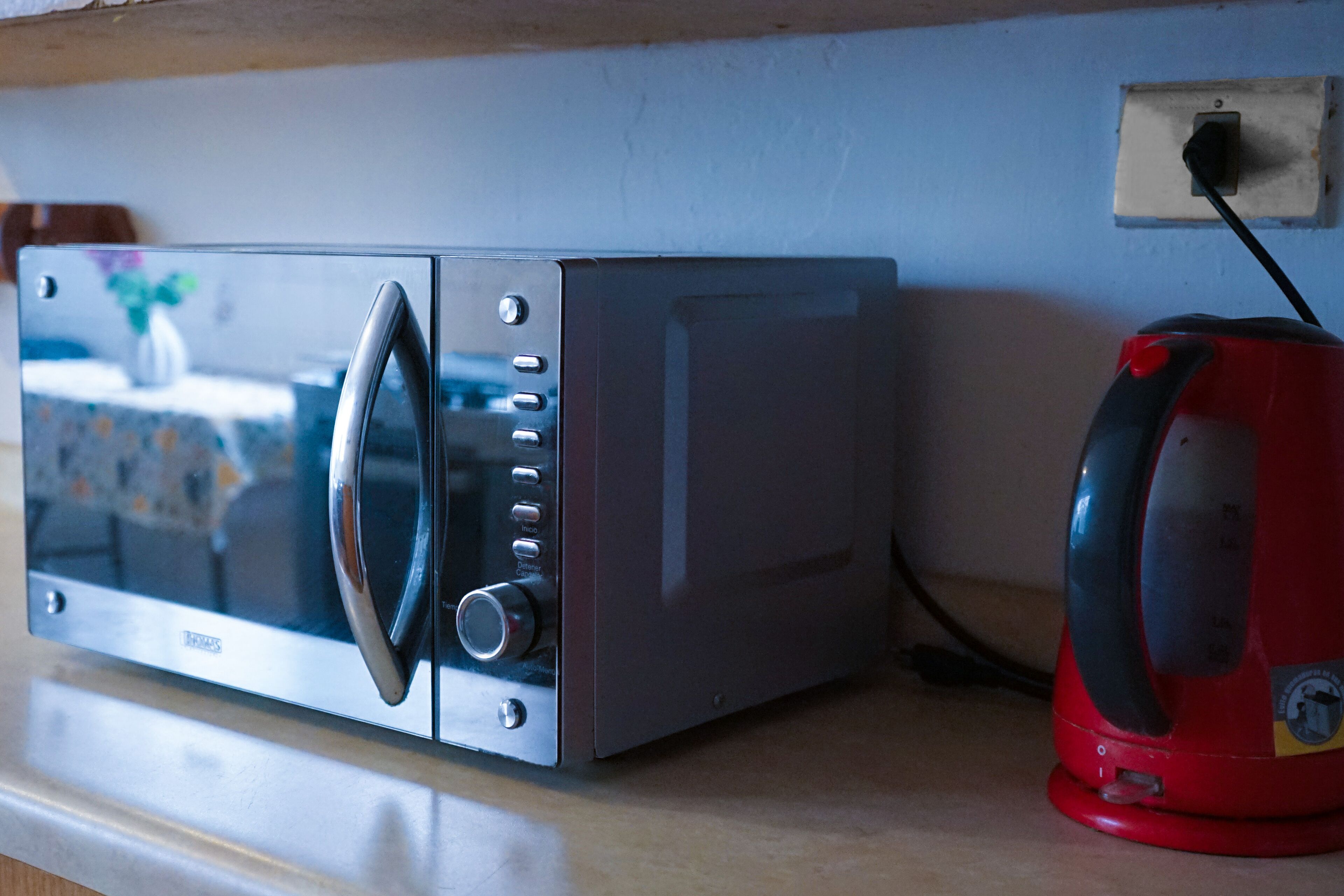 A microwave oven with a digital display and control panel, connected to a power outlet.