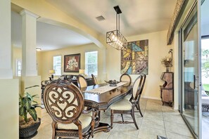 Relax in this stylish dining area with a large table, ornate chairs, and a contemporary chandelier.
