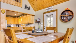 A wooden dining table with four chairs, a decorative wall clock, and a wooden ceiling. - Mountain-View Murphy Cabin w/ Shared Fire Pit (Murphy)