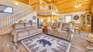 A spacious living area with a high ceiling, wooden staircase, and a cozy fireplace. - Mountain-View Murphy Cabin w/ Shared Fire Pit (Murphy)