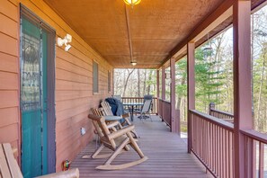 A wooden porch with rocking chairs, a table, and a view of trees. - Mountain-View Murphy Cabin w/ Shared Fire Pit (Murphy)