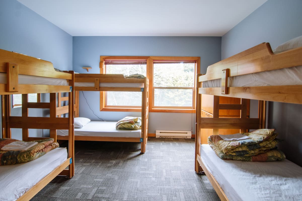 Een studentenkamer met stapelbedden, een raam en een radiator.