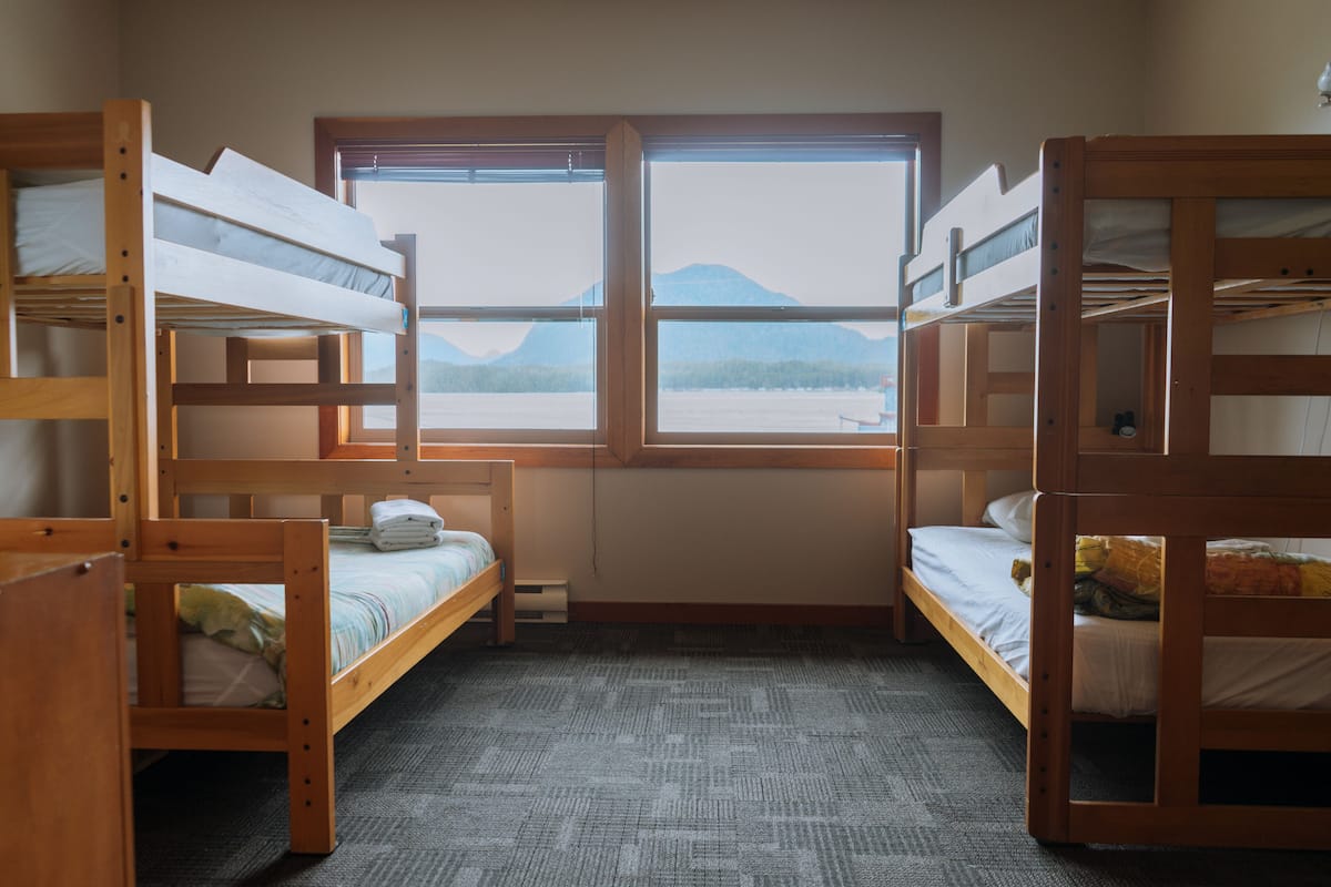 Een kamer met stapelbedden, een raam met uitzicht op bergen en een vloerbedekking.