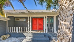 Ein Haus mit roter Tür, weißem Geländer und Stufen zum Eingang.