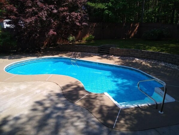 A swimming pool with a curved edge, surrounded by a brick border and a concrete deck. - Contemporary, Warm & Cozy mins to Saratoga (Ballston Spa)