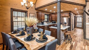 Ein Holzblockhaus-Innenraum mit Essbereich, Küche und Schlafzimmer im oberen Bereich.