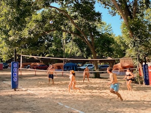 A sandy beach volleyball court with tents and cars in the background. - Son's Blue River Camp Glamping Cabin O (Kingsbury)