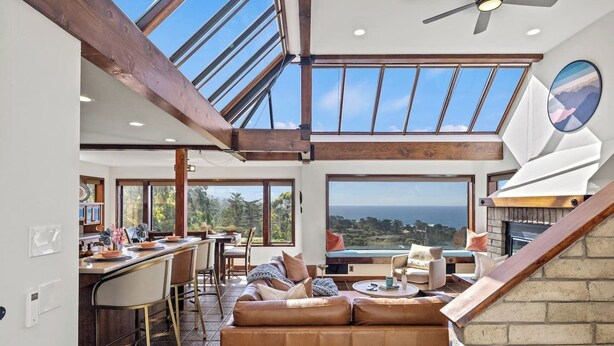 Un amplio salón con techo alto, ventanas grandes y chimenea.